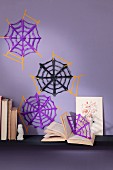 DIY-Spinnennetze aus Papier an lila Wand