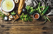 Gemüsecremesuppe mit Zucchini, Brokkoli und grünen Bohnen, Gewürze und Baguette auf Holzuntergrund