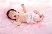 Newborn baby girl in pink nappy,yawning