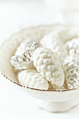 Pine-cone Christmas decorations in a porcelain dish