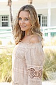 Blond woman wearing beige off-the-shoulder top with lace inserts