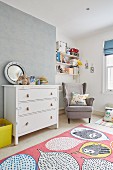 Kinderzimmer mit Ohrensessel und weißer Schubladenkommode