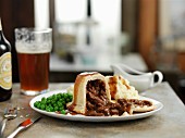 Steak and kidney pudding with peas