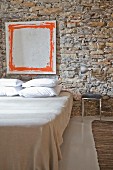 Modern artwork on rustic stone wall in minimalist bedroom