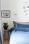 Blue bed linen, stool used as bedside tale and photos decorating wall in bedroom