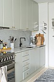 Helle Einbauküche mit Oberschränken, Marmor-Küchenarbeitsplatte und Spritzschutz