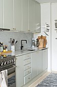 Pale fitted kitchen with wall units, marble worksurface and marble splashback