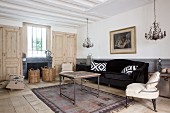 Black velvet sofa, vintage coffee table, easy chair and plain panelled wooden doors in living room