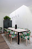 Dining area with an elongated dining table, upholstered chairs with Asian floral patterns and a white pendant lamp
