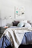 Woolen blanket over cozy bed with lots of different pillows