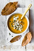 A bowl of pumpkin soup with feta cheese and pumkin seeds