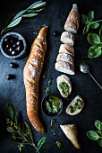 Baguettes with pesto, olives and basil leaves (seen from above)