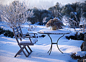Sitzplatz im winterlichen Garten mit Strauß aus getrockneten Zweigen und Blüten