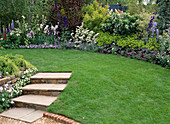 Treppe im Garten mit Natursteinmauer, Rasen und Blumenbeet