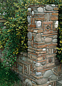 Kustvoll gestaltete Steinmauer und Pfosten aus Kieselsteinen