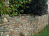 Kunstvoll gestaltete Steinmauer aus Kieselsteinen und diversen Ziegelsteinen
