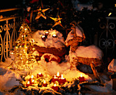 Weihnachtsstimmung mit Kerzen und Lichterkette draußen im Schnee
