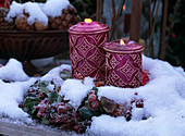 Candles in dried wreath in snow, pink
