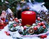 Tellerkranz mit Nordmanntanne, Limettenscheiben, rote Christbaumkugeln, rote Kerze