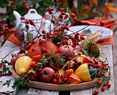 Tonschale mit Rosa (Hagebutten), Cucurbita (Kürbissen), Physalis (Lampionblume)