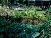 Kleiner bepflanzter Teich vor offenem Wintergarten mit Korbmöbeln