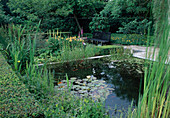 Formal garden with pond and shrub beds, bordered by hedges, bench