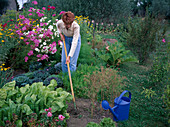 Loosen soil between summer flowers and vegetables with a rake, anthemis (dyer's chamomile), cosmos (jewelweed), cabbage, savoy cabbage (brassica), carrots, carrots (Daucus carota), chard (Beta vulgaris), watering can