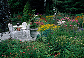 Terrace with white seating area framed by flowering perennials