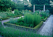 Buxus (box) hedges with perennials, Lavandula (lavender), paths with clinker and water-bound surface, bench between columns.