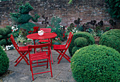 Terrace with red seating area between Buxus (boxwood) cut into various shapes