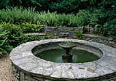Bricked round fountain, dry stone wall with ferns