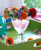 Weinglas mit rosa Schwimmkerzen und Kranz aus Zinnia (Zinnien)