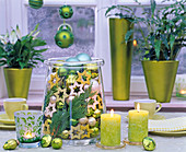 Glasgefäß, gefüllt mit grün und cremefarbenen Kugeln und Holzsternen