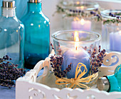 Glas dekoriert mit Lavandula (Lavendel), blaue Kugelkerze, weißes Tablett