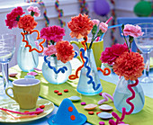 Dianthus (carnation) in frosted bottles on green table runner