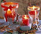 Glass lanterns filled with sand and decorated with pink (rosehips)