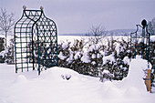 Snowy garden bed with metal arbour and climbing frame