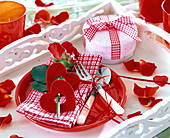 Rosa (Rose, rot), dekoriert mit roten Filzherzen, auf karierter Serviette
