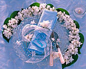 Blüten und Blätter von Syringa (Flieder, weiß) kranzförmig um Glasteller