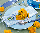 Small Taraxacum bouquet on blue and white striped napkin