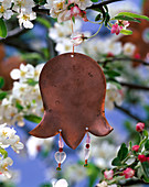 Copper pendant in flower form on branch of Malus (apple)