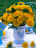 Strauß aus Taraxacum (Löwenzahn) in blau-weißer Vase mit Hahnenmotiv