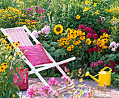 Folding deck chair on the flowering bed with Rudbeckia fulgida and hirta