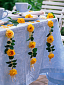 Rose flowers and leaves with needles attached to ribbons