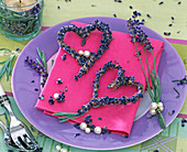Herzen und Sträußchen aus Lavandula (Lavendel) auf pinkfarbener Serviette