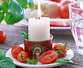 Lycopersicon (Tomaten) halbiert und ganz, Ocimum (Basilikum), weiße Kerze