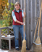 Care of garden tools: Woman oils wooden handle of broom