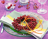 Wreath of pink (rosehips) on napkin, glass plate, cutlery