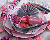 Serviettendekoration mit rosa Serviette, silbernem Fächer aus Geschenkpapier