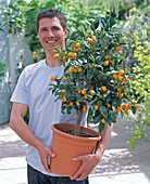 Junger Mann mit Fortunella japonica (Kumquat)